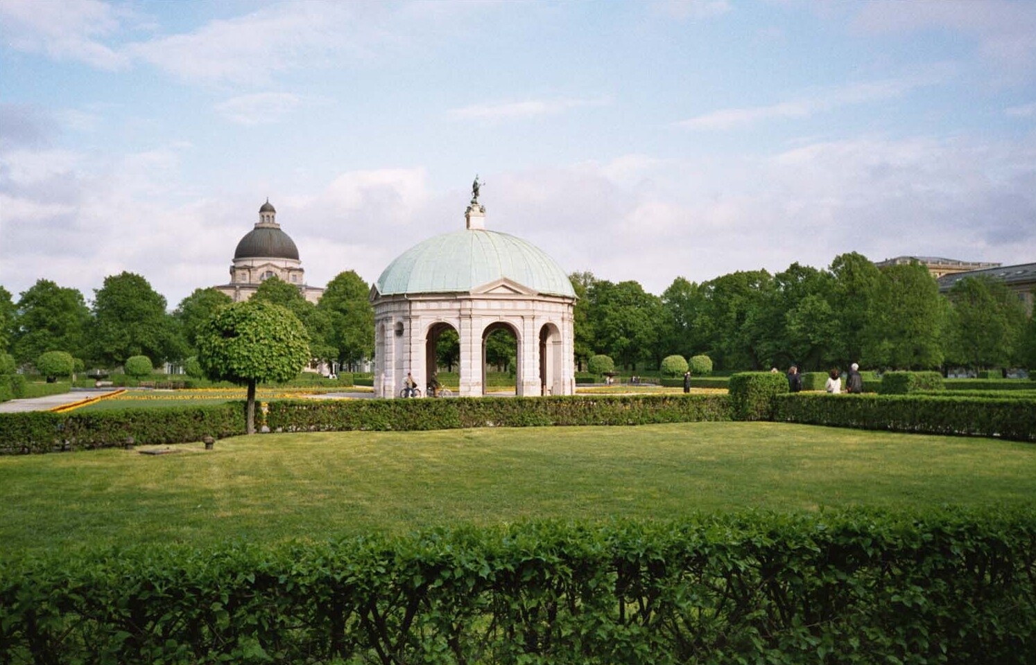 Diana pavilion surrounded by green hedges and flower beds in Hofgarten